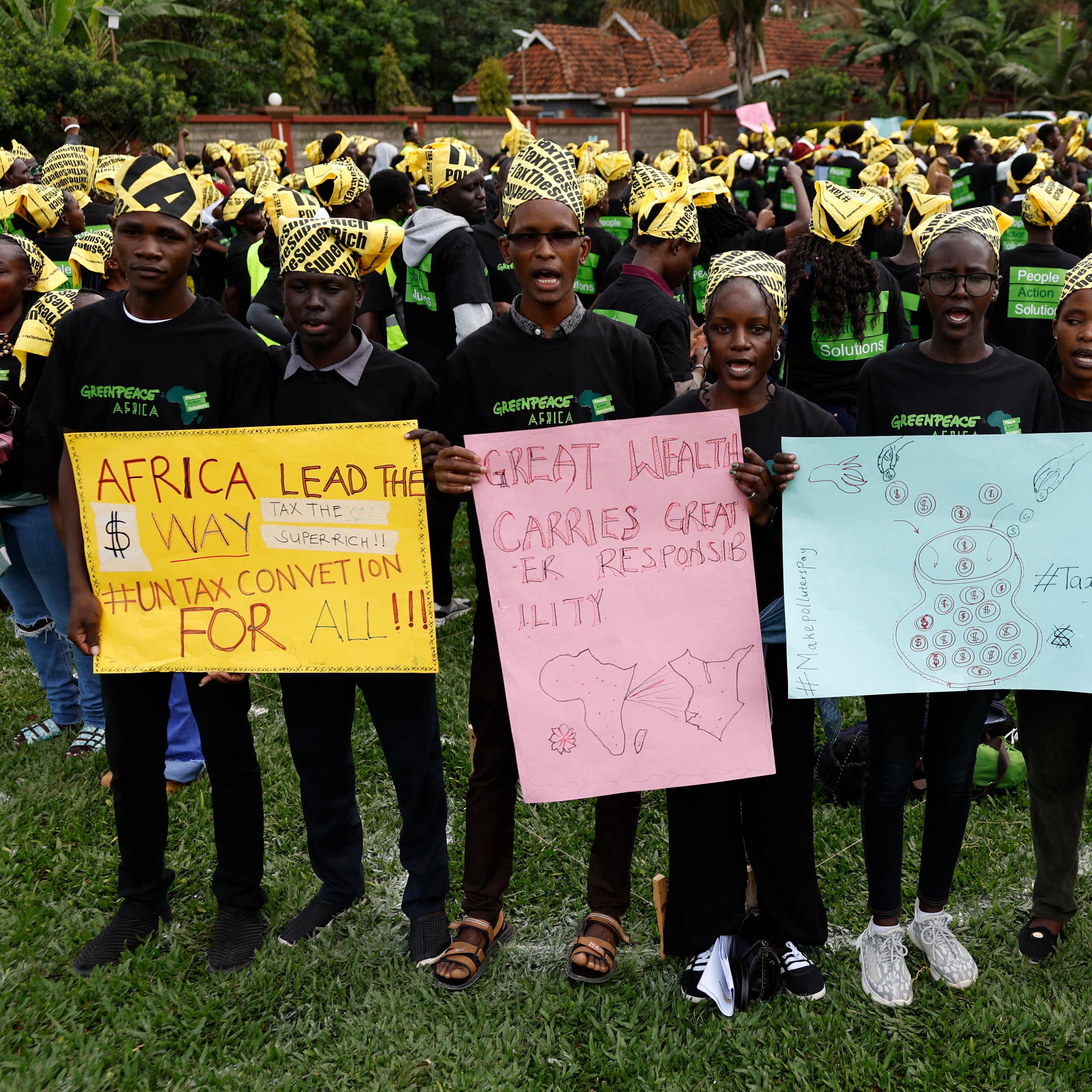 Protestors holding up placards reading 'Great Wealth Carries Greater Responsibility', 'Tax the Super Rich', 'Africa lead the way: UN Tax Convention for all'