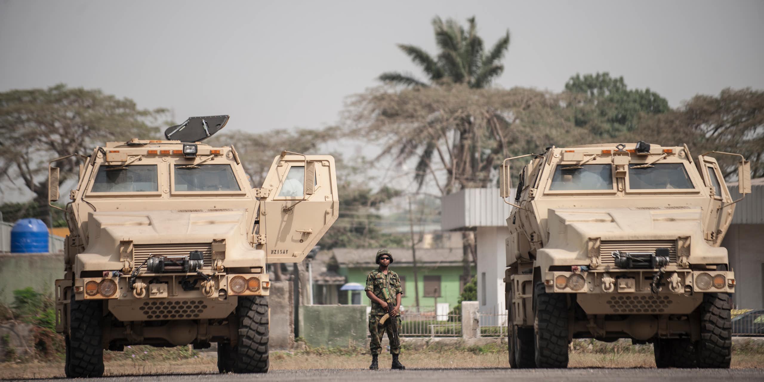 A soldier standing in between armoured vehicles