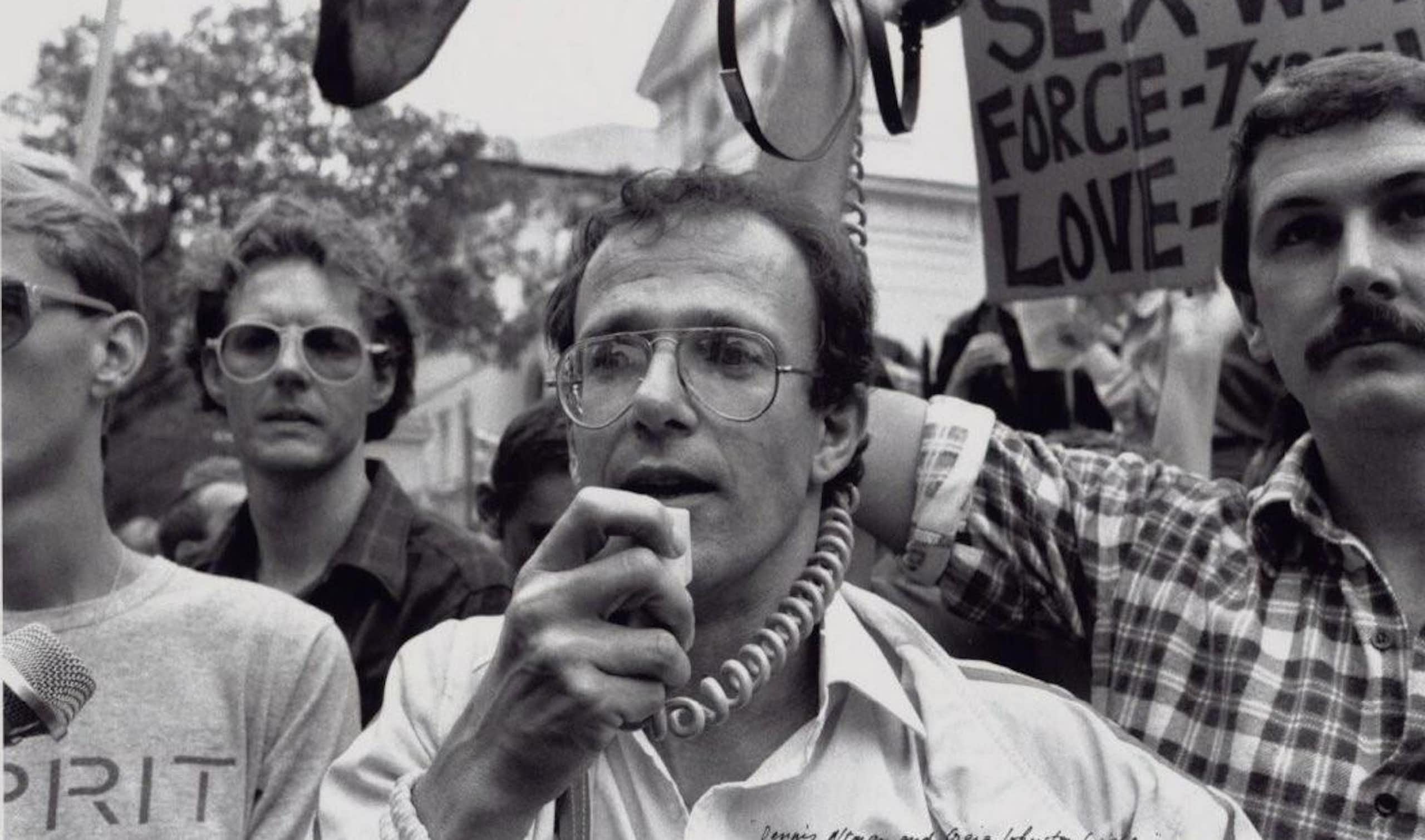 a man with glasses talking into a megaphone at a rally