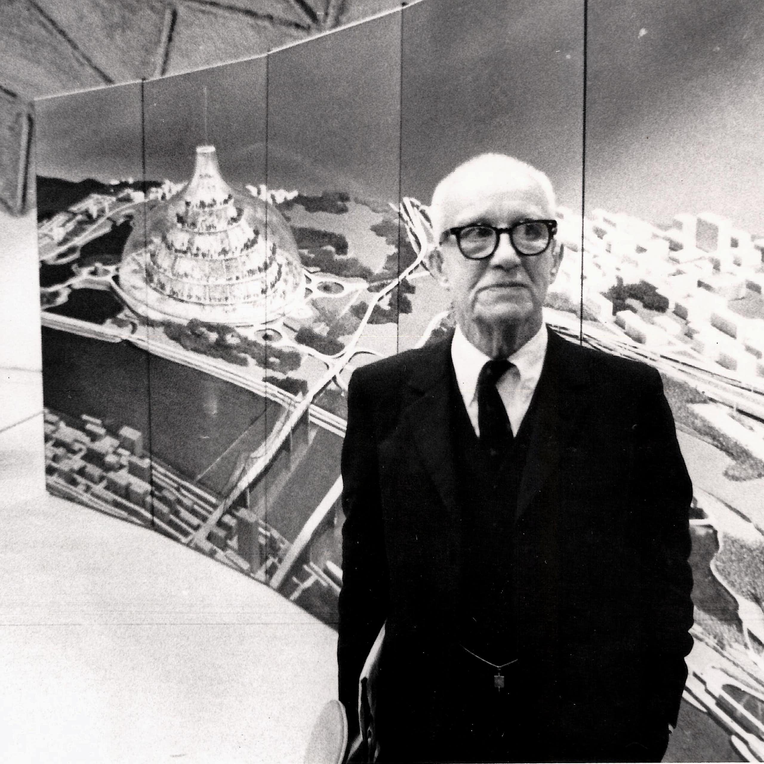 Buckminster Fuller stands in front of a large image of his radical design for a domed city, 1971.