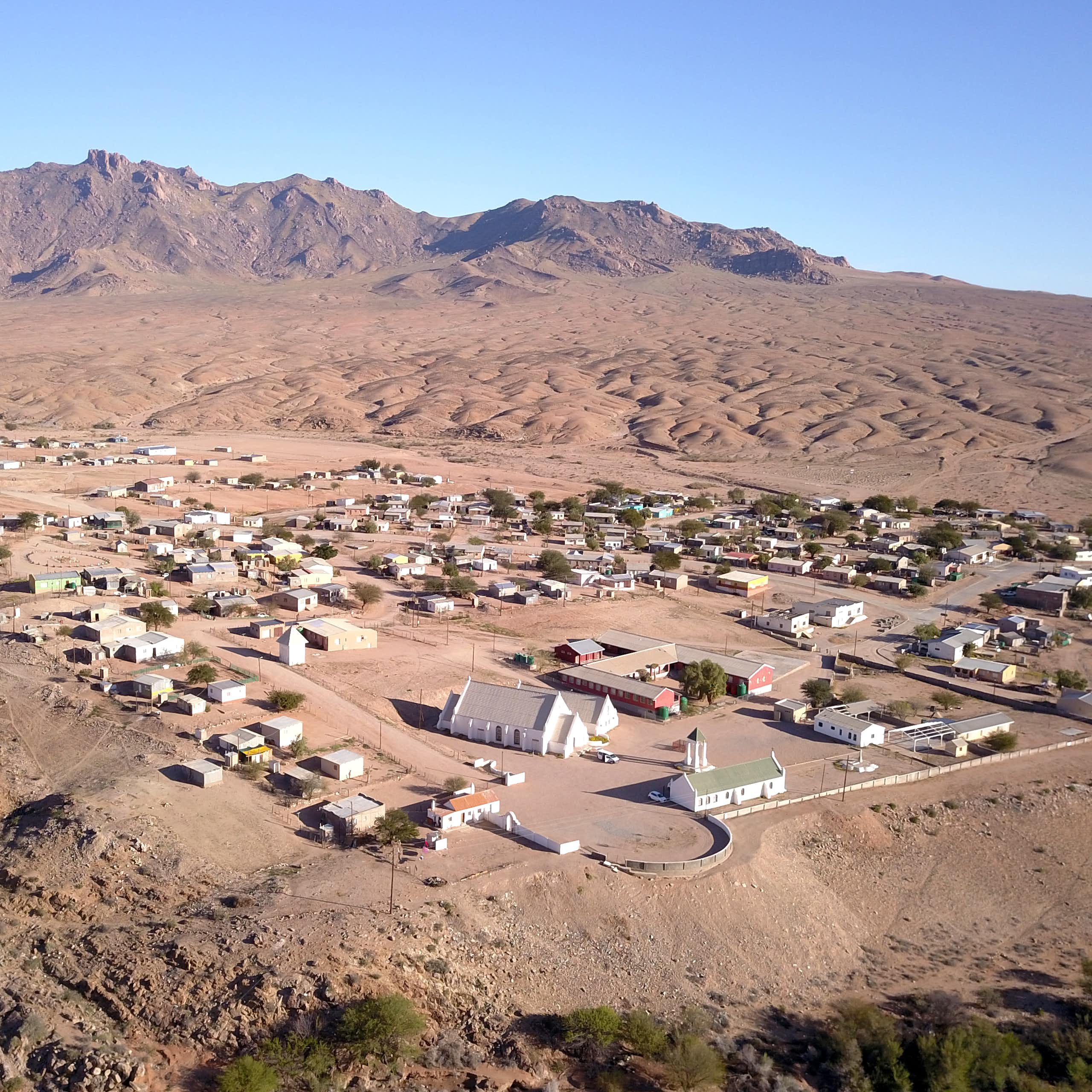 A small town of about 50 houses, no trees and a brown desert background with some treeless mountains nearby