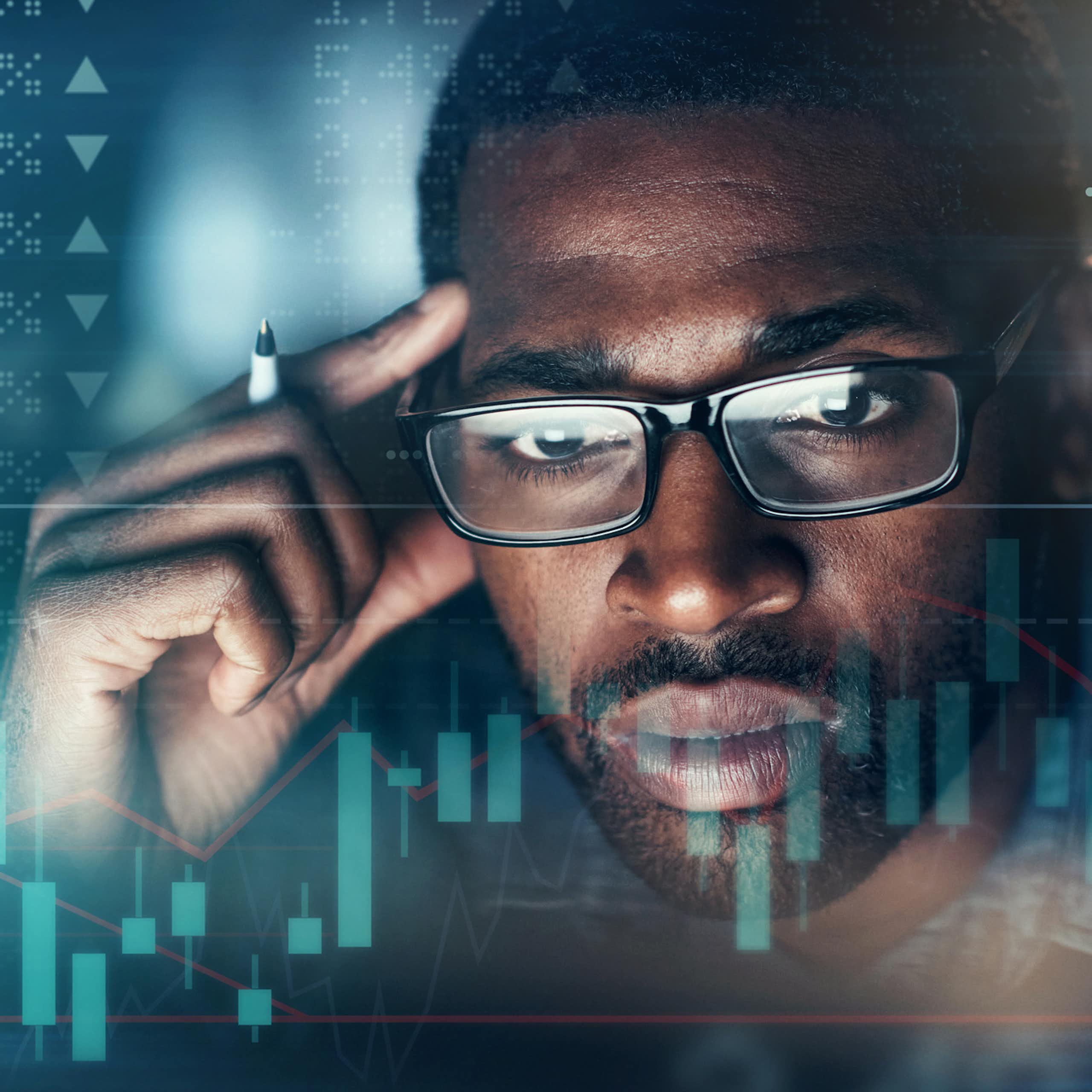 A man stares at numbers and graphs on a screen