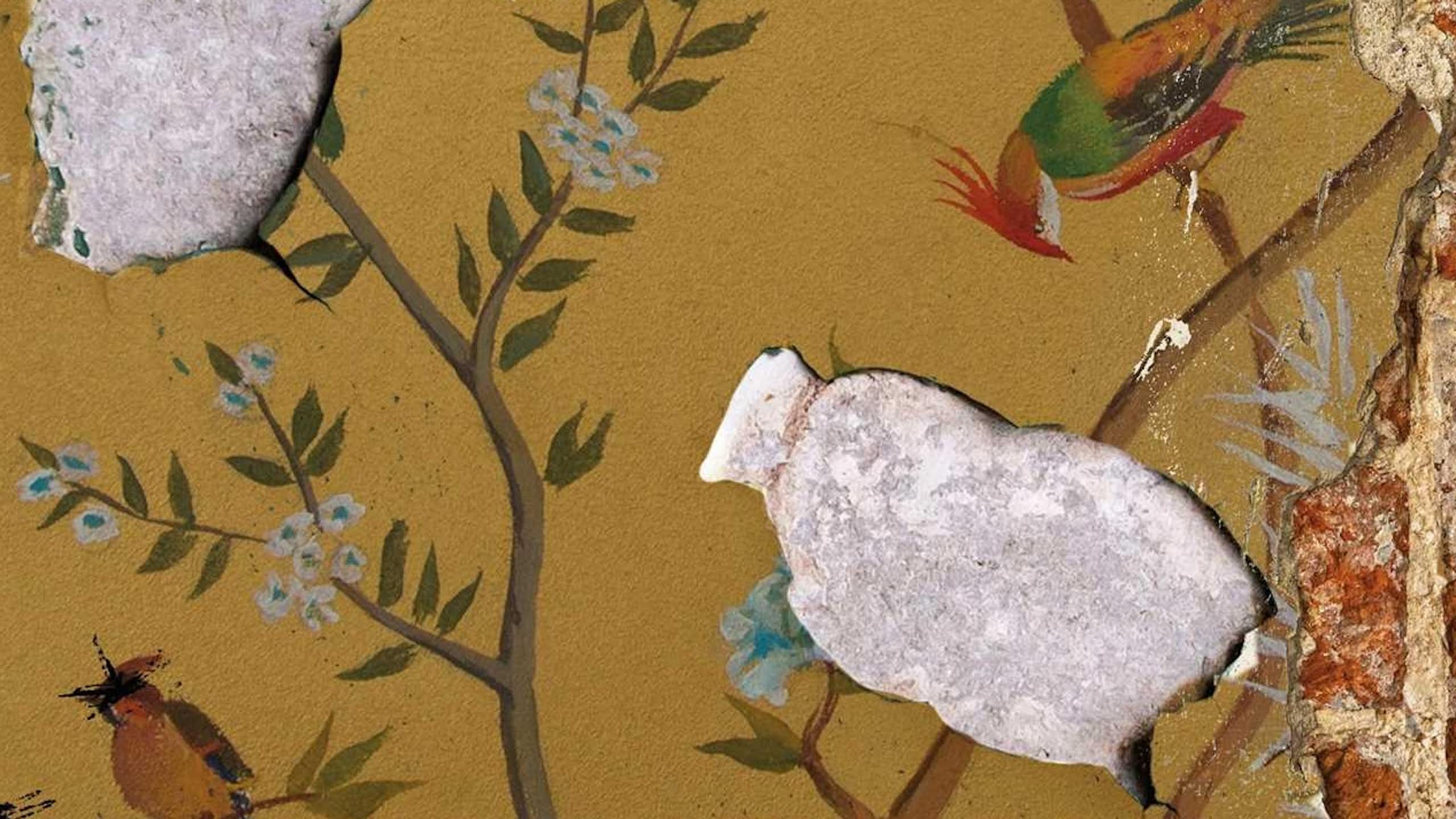 Old wallpaper showing birds in delicate branches of a tree is peeling, revealing cemenrt beneath it.
