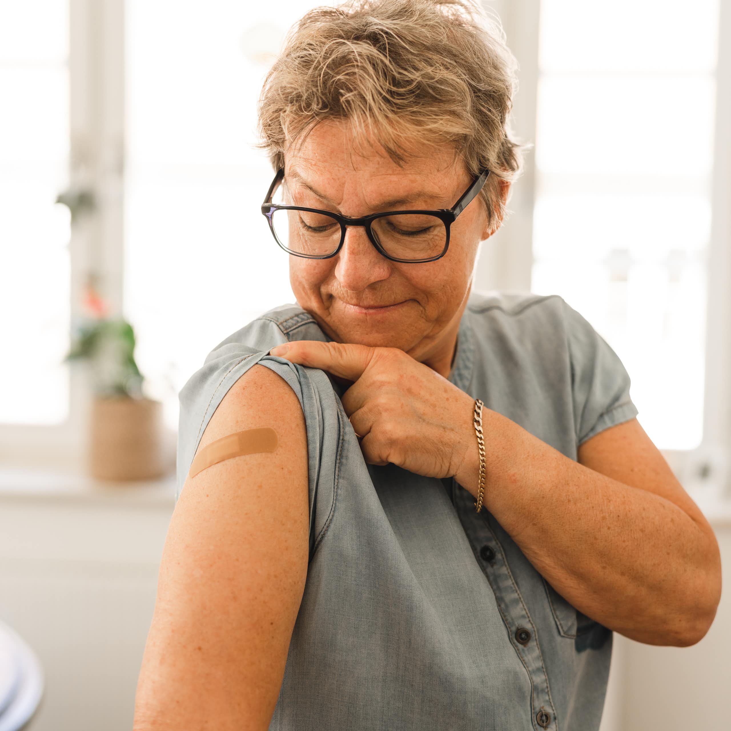 Woman looks at a bandaid on her arm after getting vaccinated