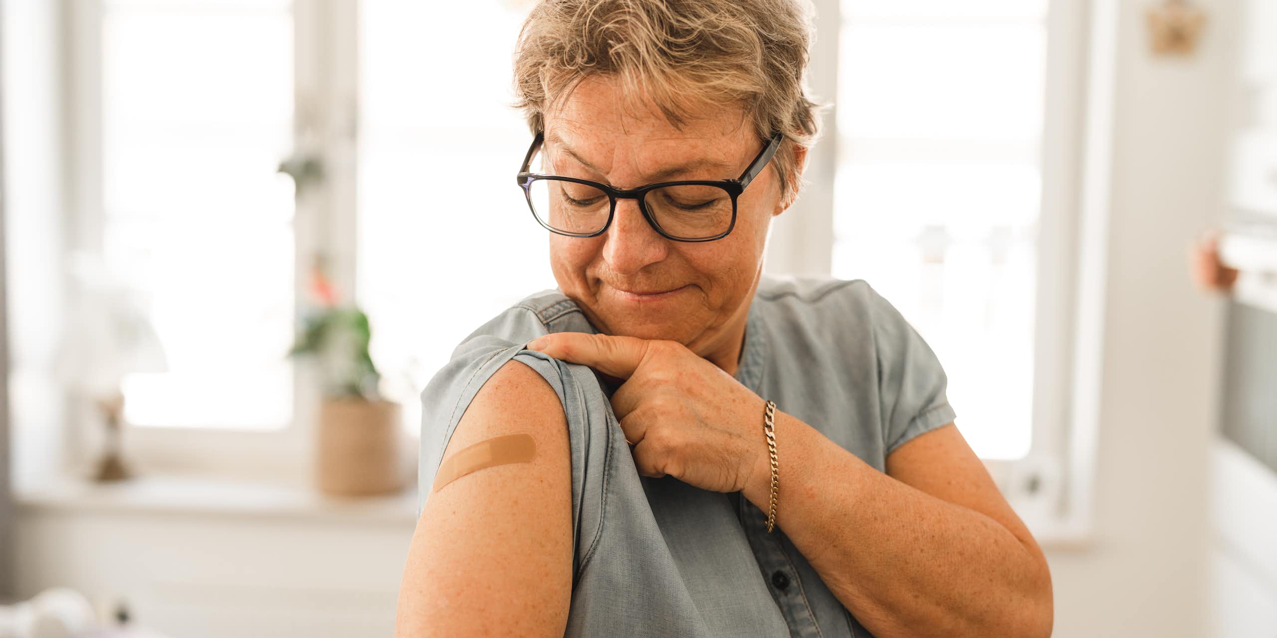 Woman looks at a bandaid on her arm after getting vaccinated
