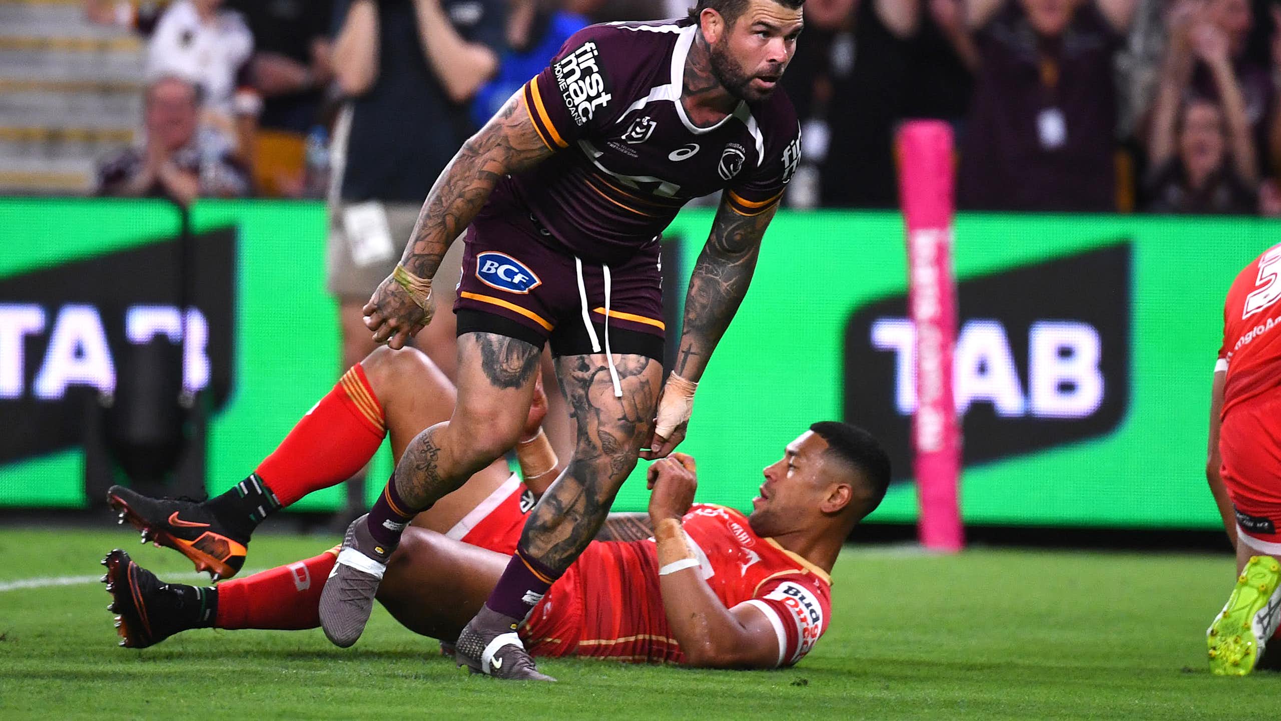 Adam Reynolds of the Broncos scores a try against the Dolphins, with TAB signage showing on the sidelines.